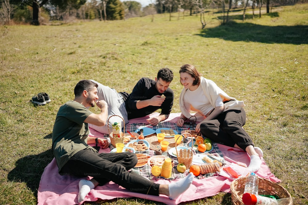 a group of people sitting on top of a pink blanket