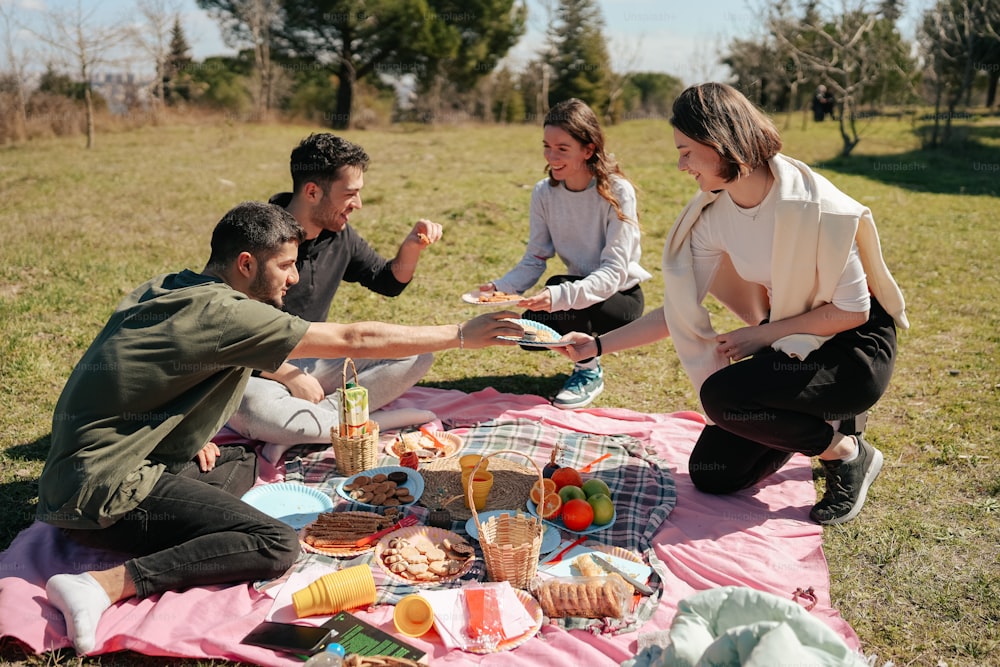 a group of people sitting on a blanket eating food