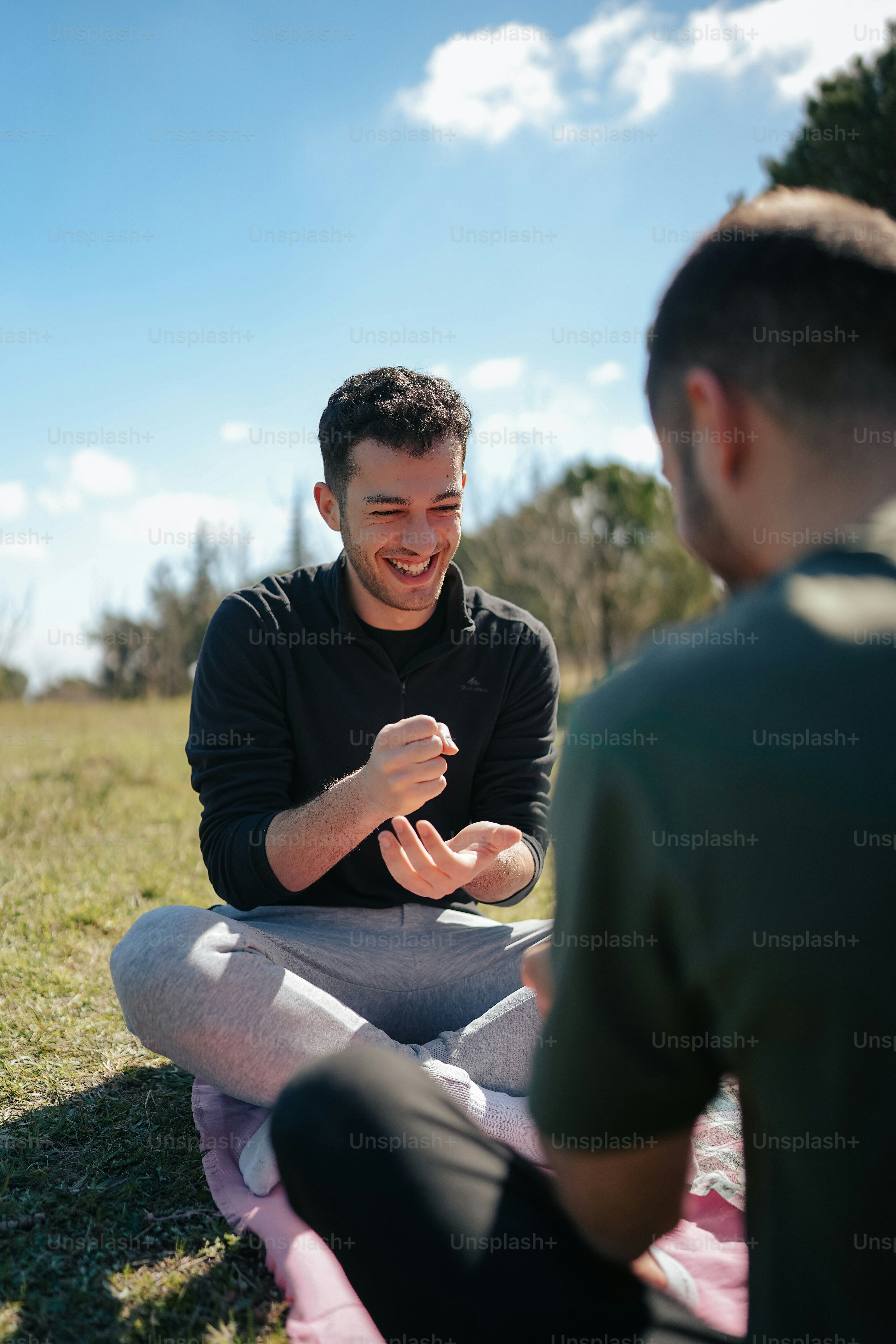毛布の上に座って別の男と話している男