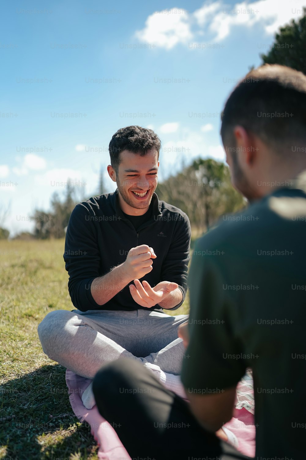 a man sitting on a blanket talking to another man