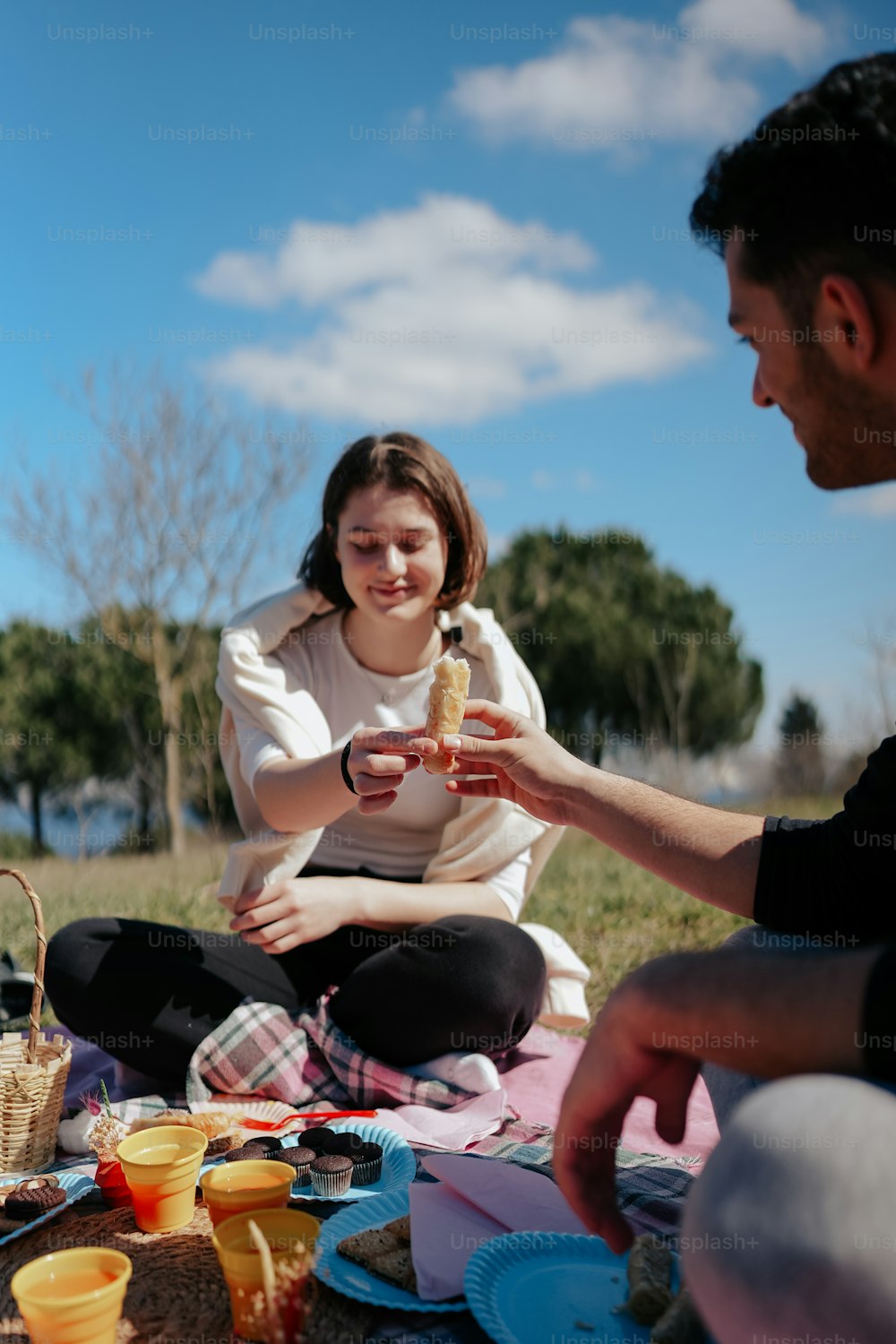 um homem e uma mulher sentados em um cobertor comendo comida