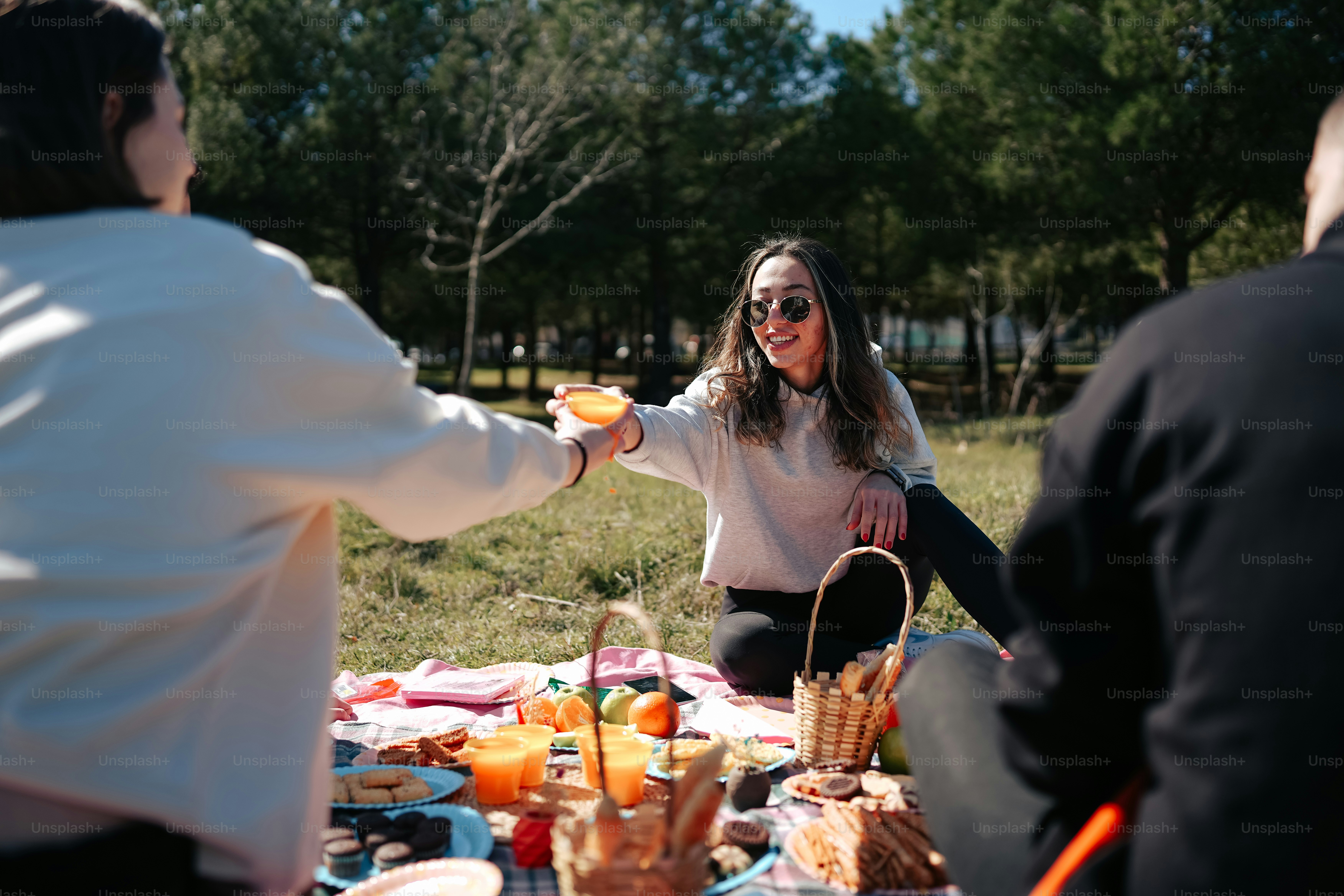 a woman sitting on a blanket holding a plate of food