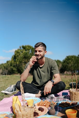 a man sitting on a blanket eating food