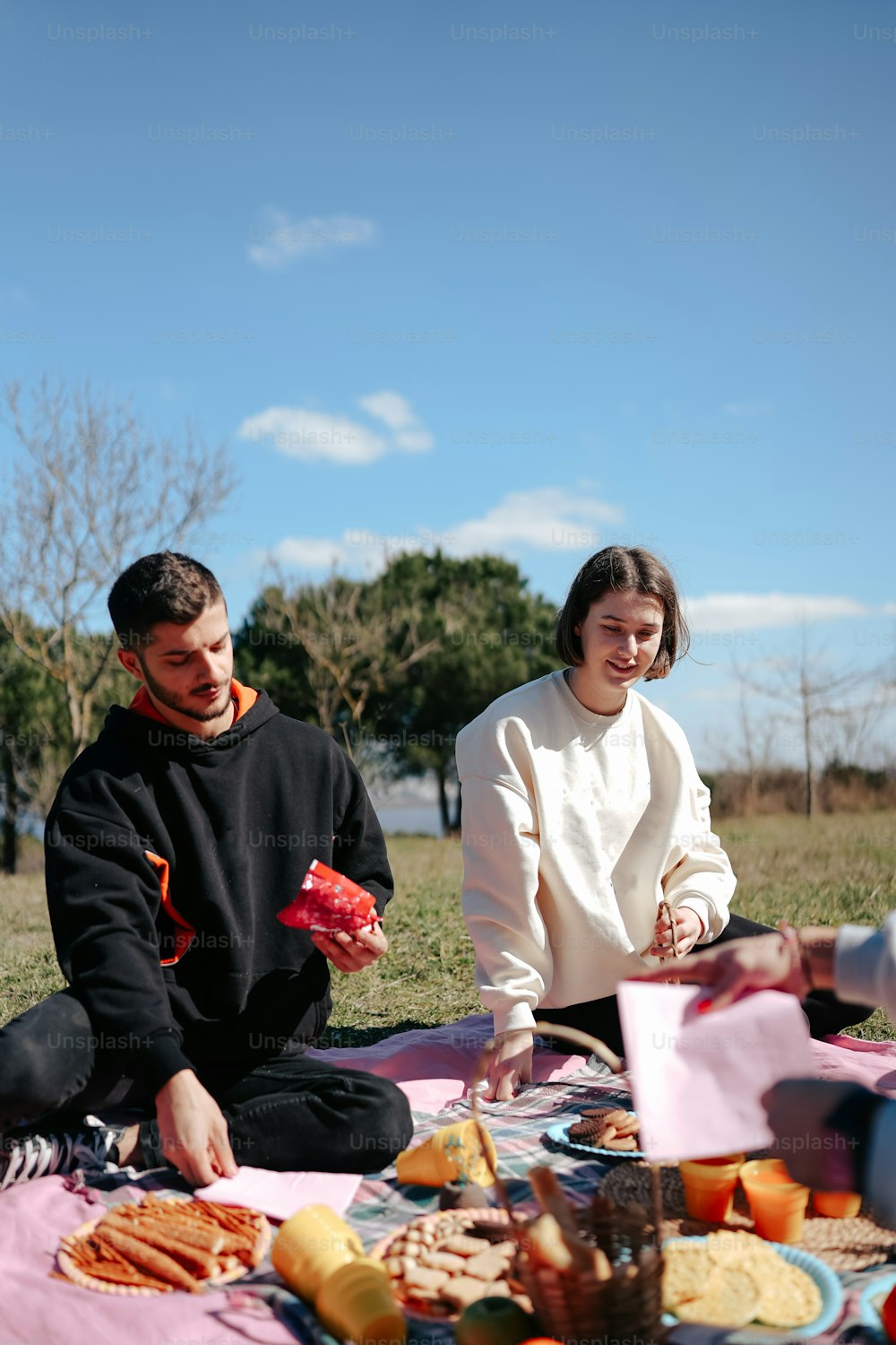 a man and a woman sitting on a blanket eating food