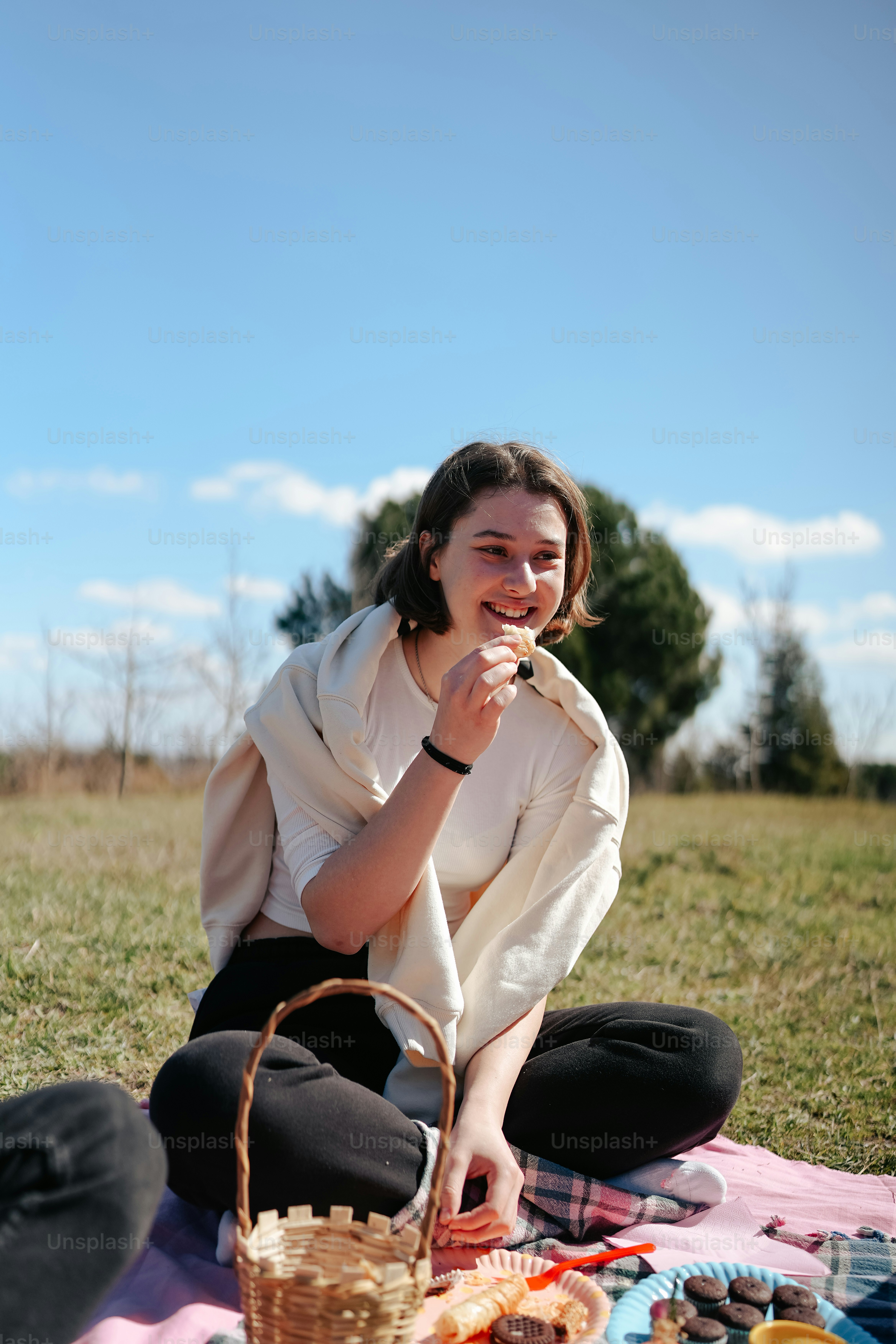 a woman sitting on a blanket eating food