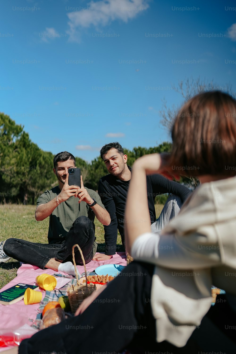 a man and woman sitting on a blanket with a cell phone