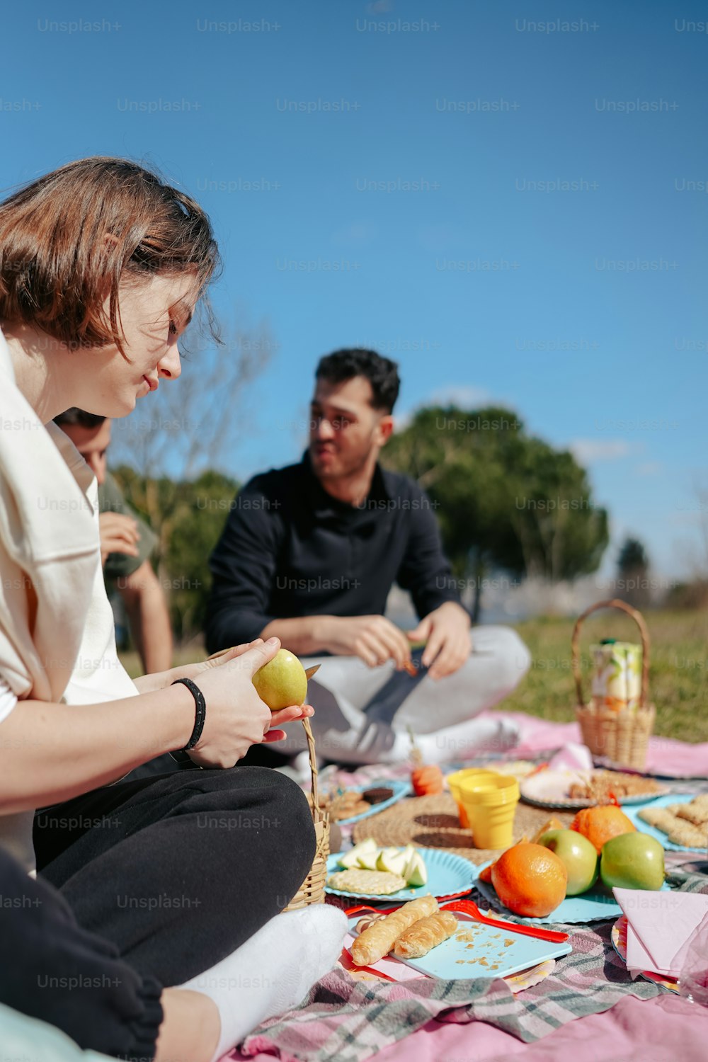 Un uomo e una donna seduti su una coperta che mangiano cibo