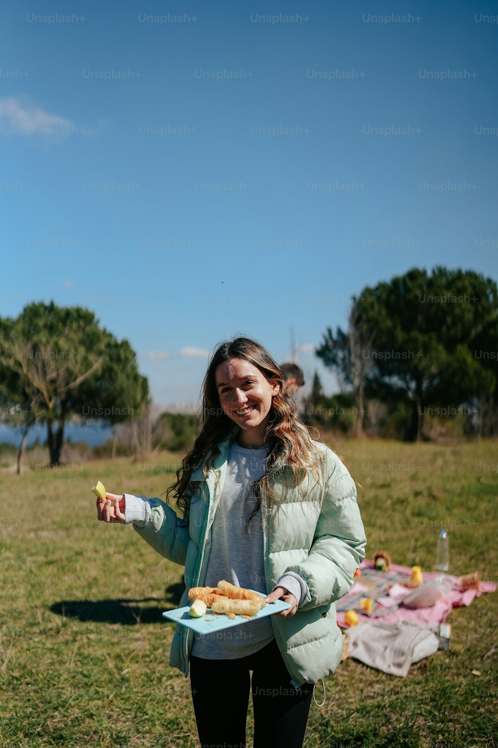 a woman holding a plate of food in a field