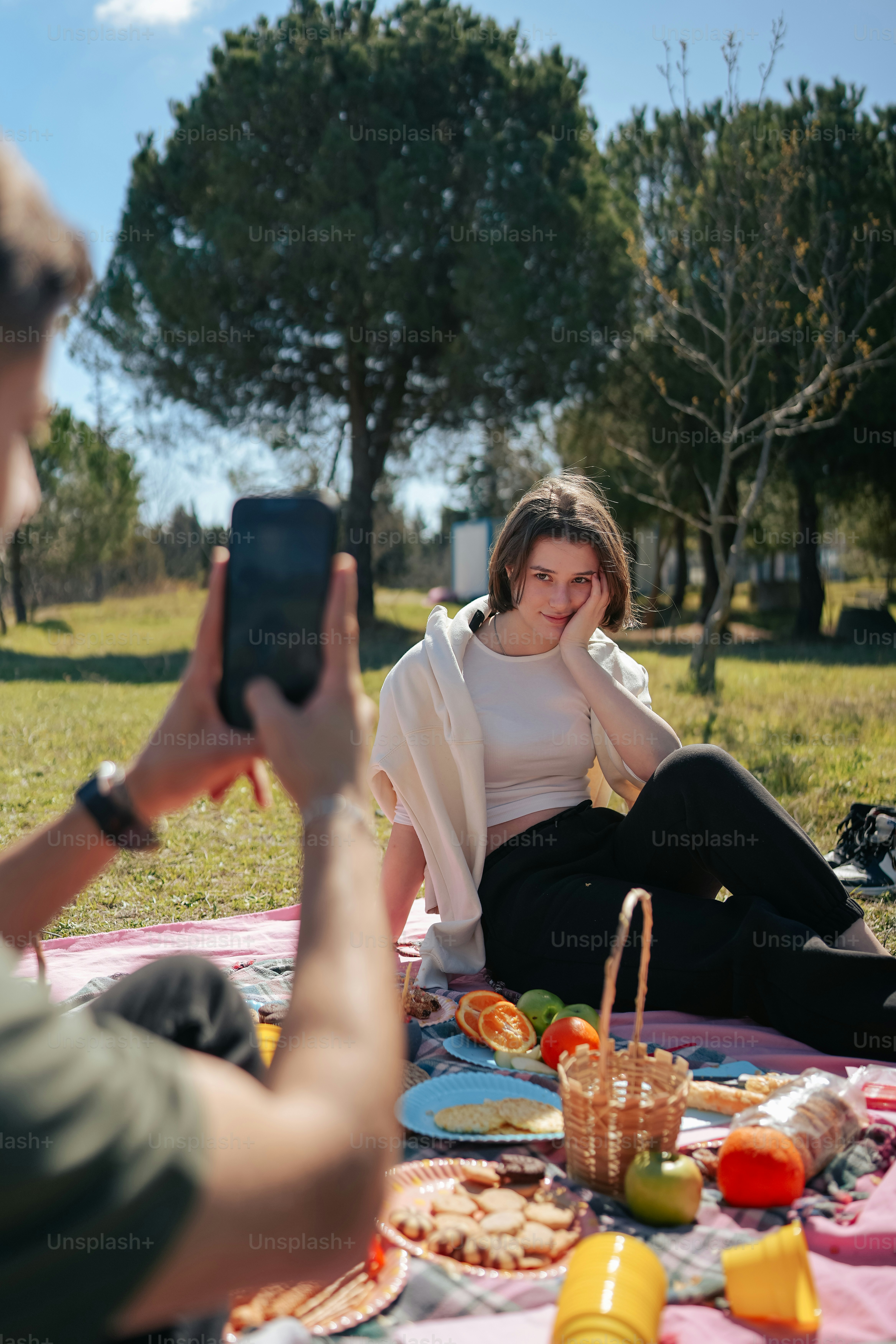 a woman sitting on a blanket taking a picture of herself