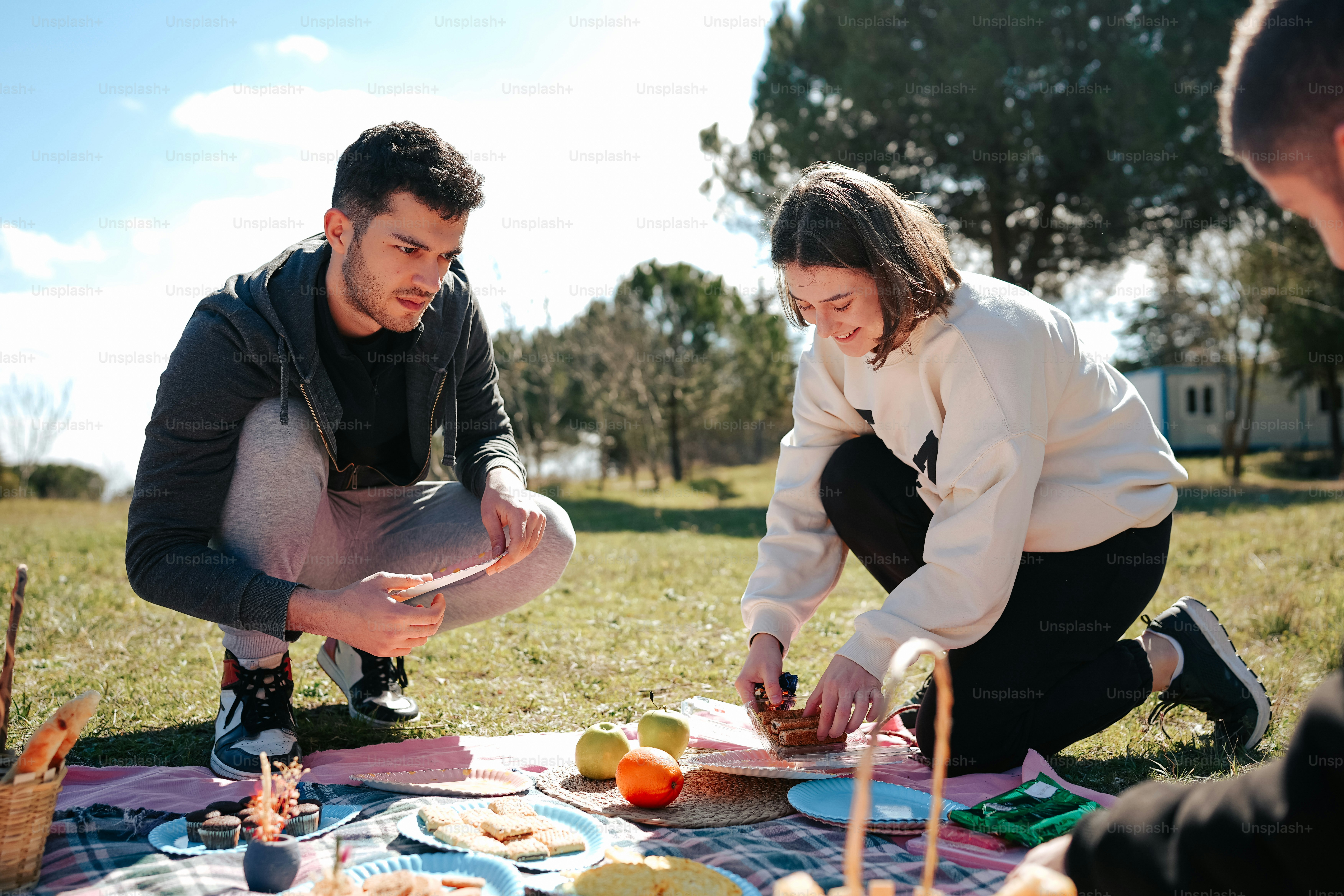a man and a woman sitting on a blanket in the grass