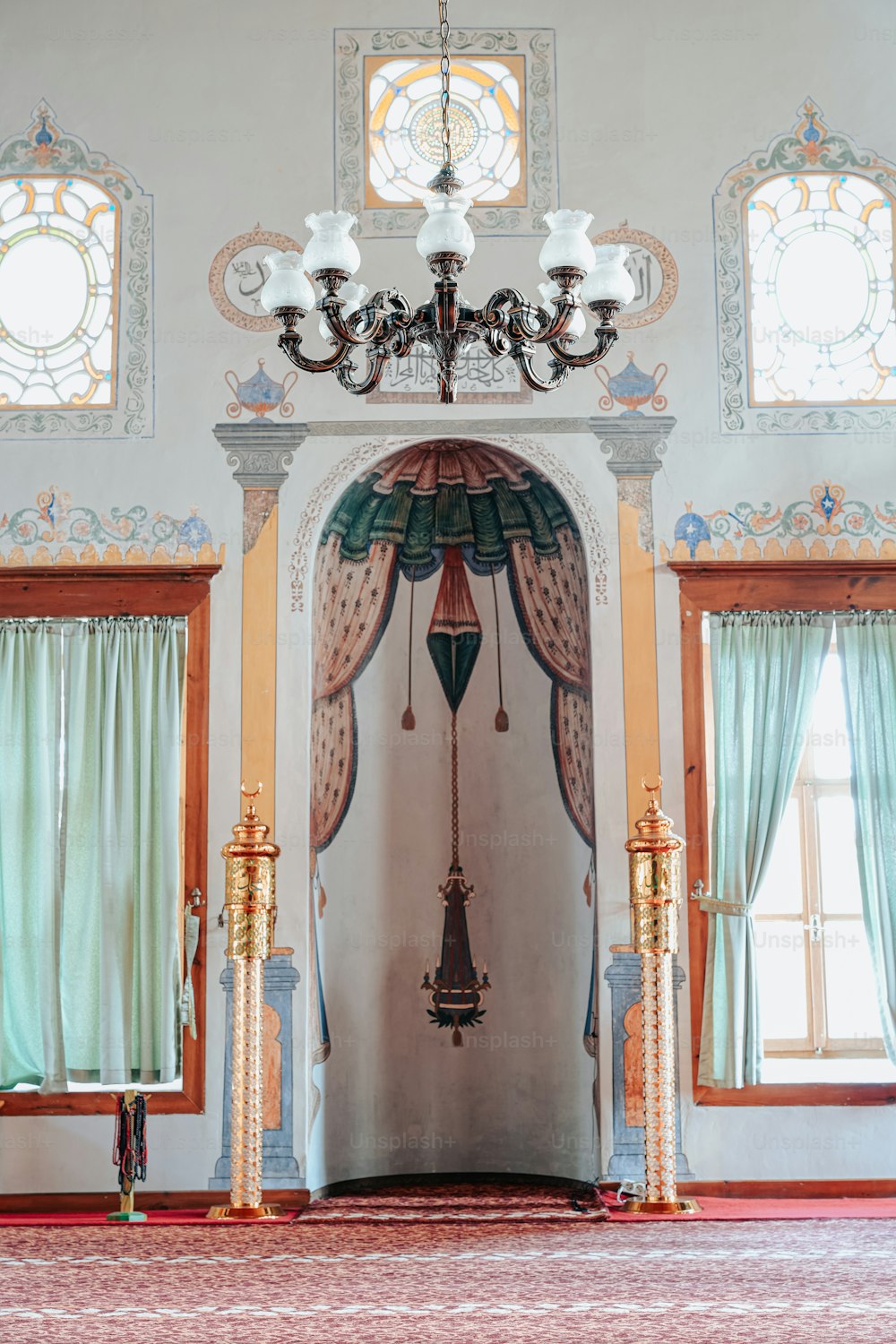 a room with a chandelier and two windows
