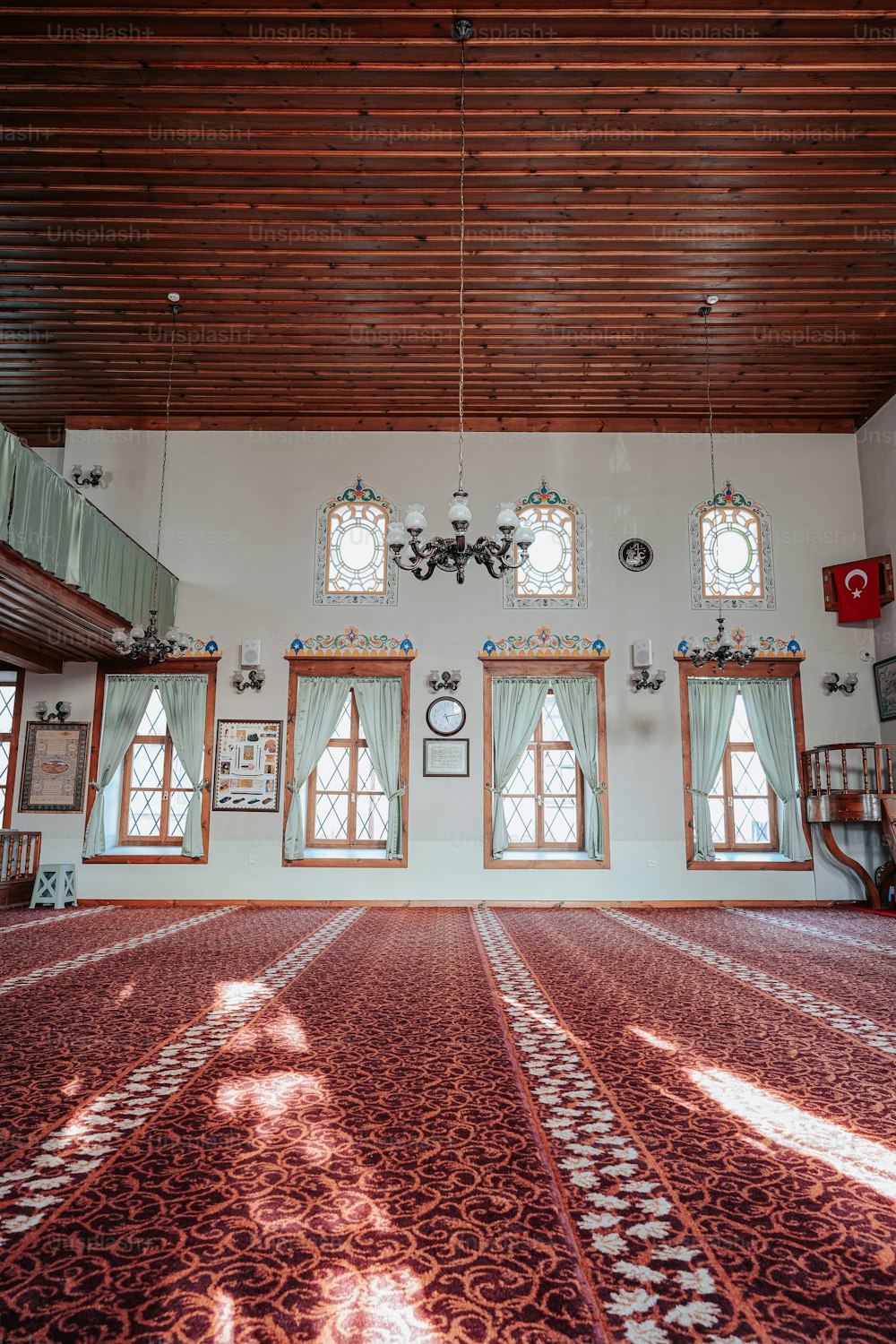 Ein großer Raum mit mehreren Fenstern und einem Teppich auf dem Boden