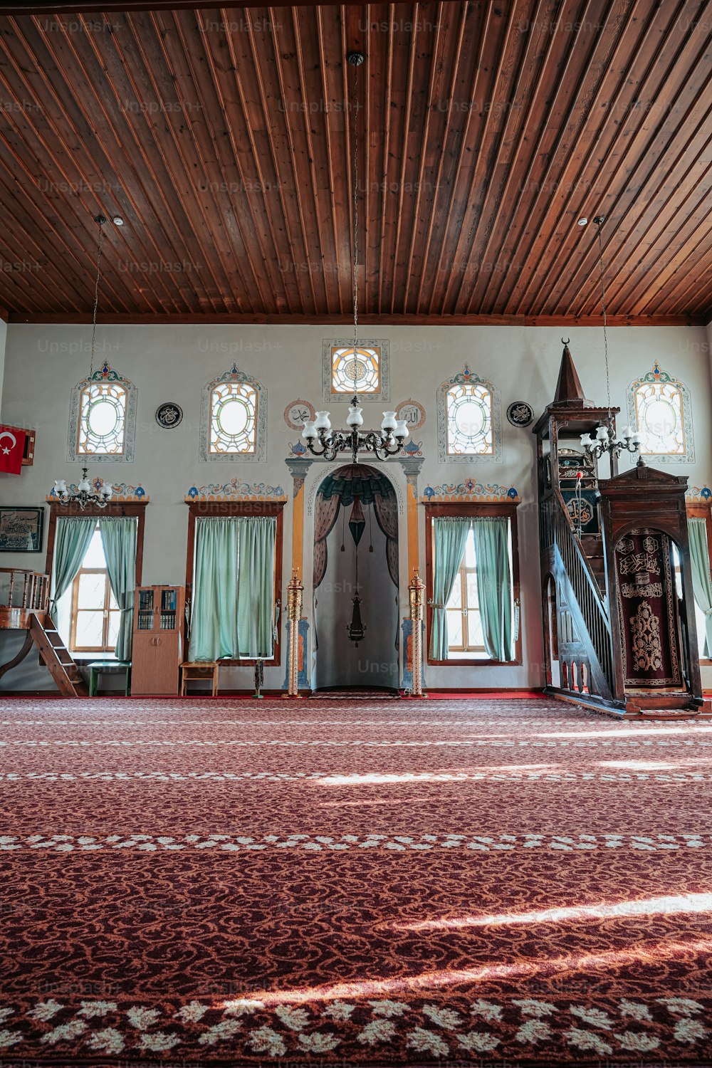 una grande stanza con un tappeto rosso e diverse finestre