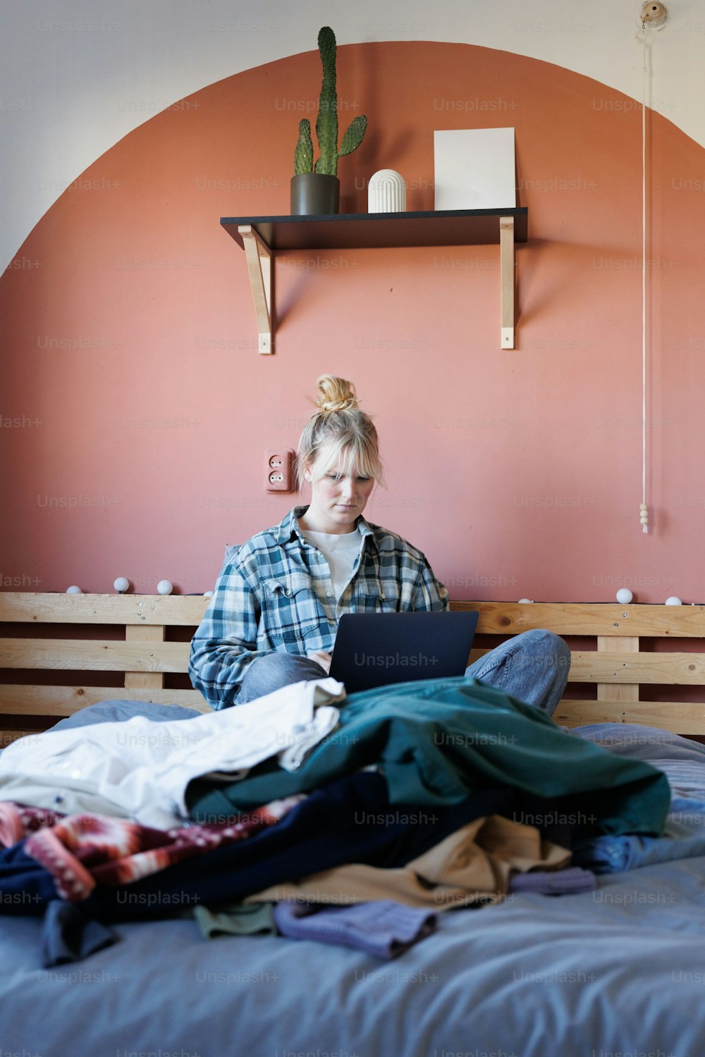 Eine Frau, die mit einem Laptop auf einem Bett sitzt
