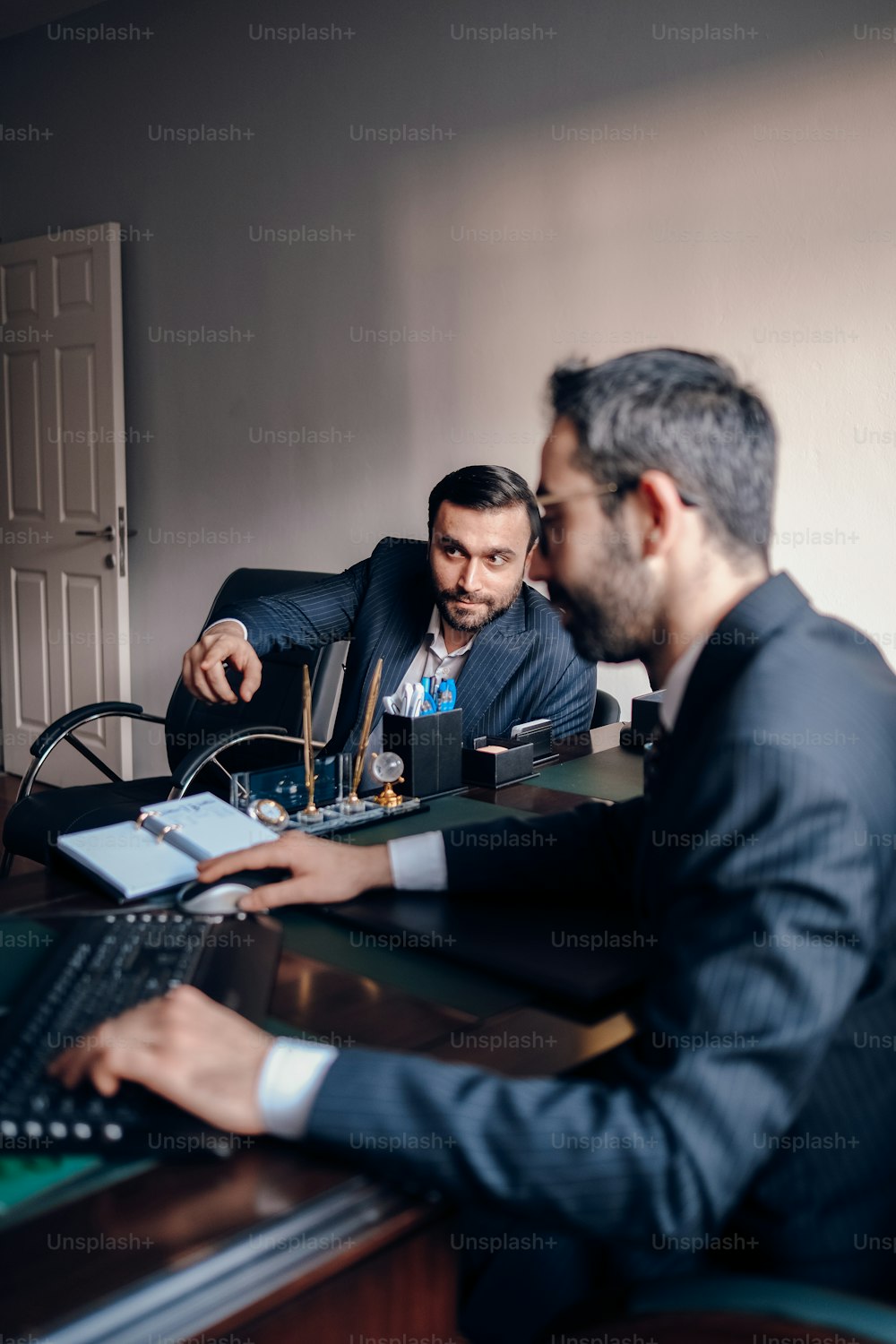 Dos hombres sentados en un escritorio con una computadora portátil
