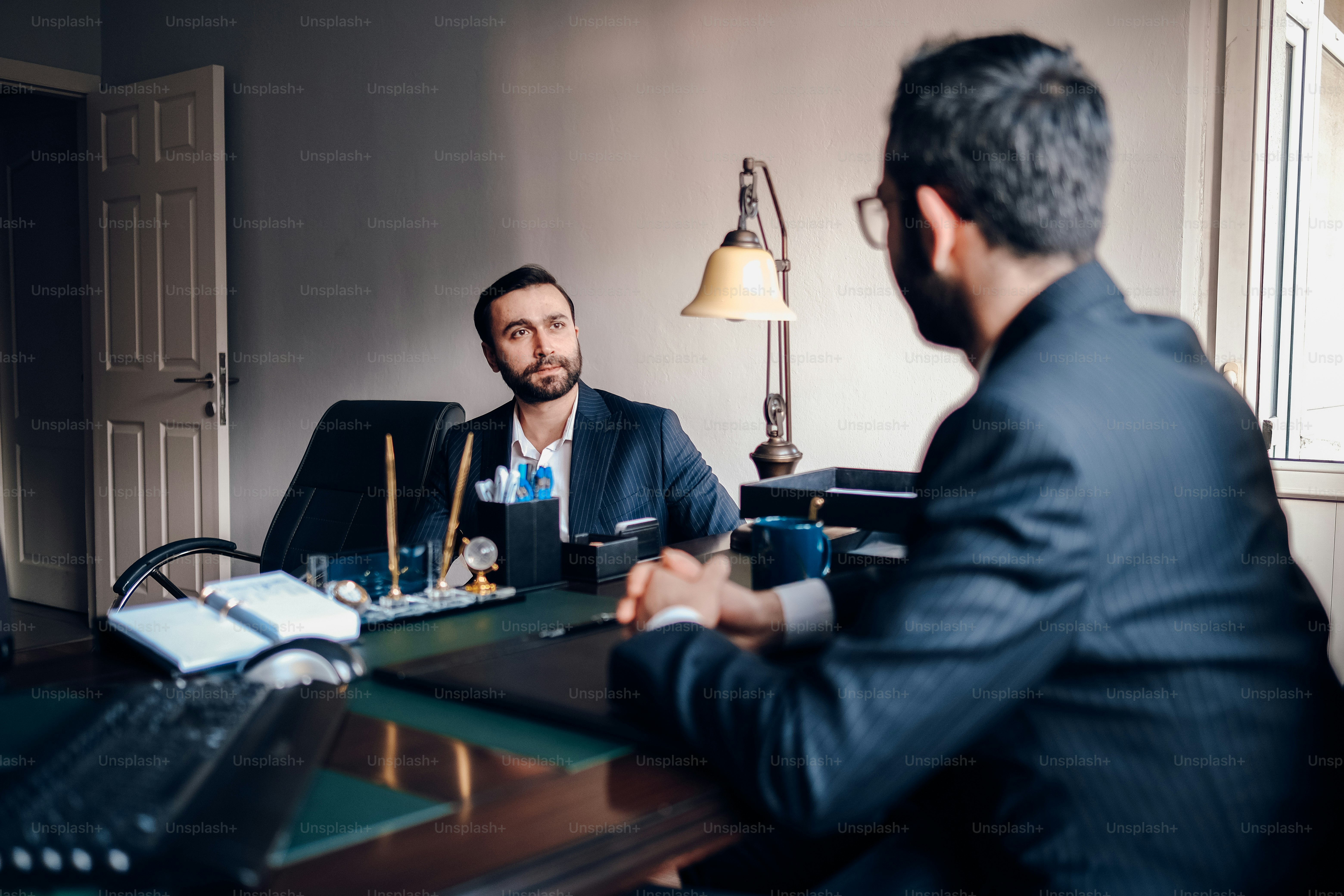 a man sitting at a desk talking to another man