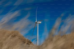 a wind turbine on a hill with a blue sky in the background