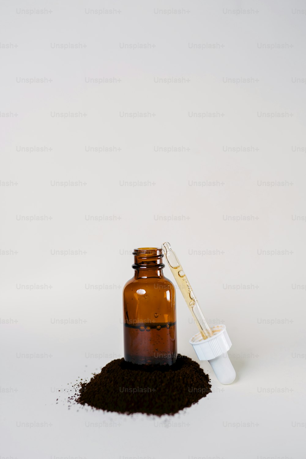 a brown bottle with a scoop of dirt next to it
