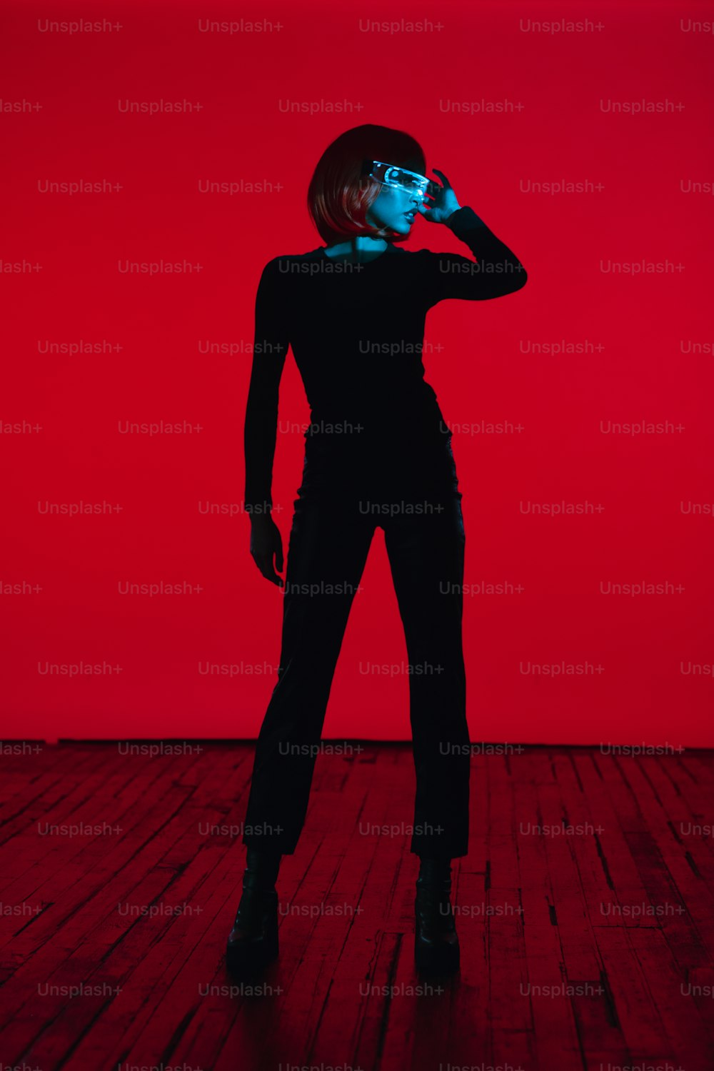 uma mulher de pé em um piso de madeira na frente de uma parede vermelha