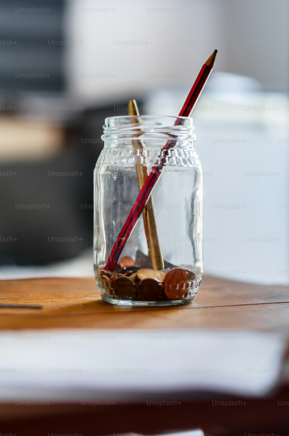 a glass jar with two red straws and a wooden spoon