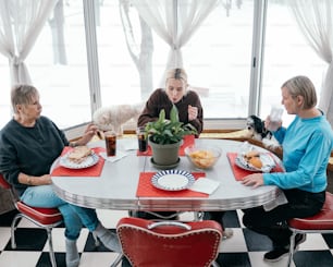 a group of women sitting around a table eating food