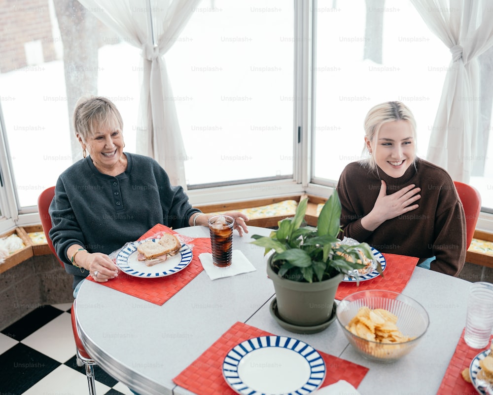 two people sitting at a table with plates of food