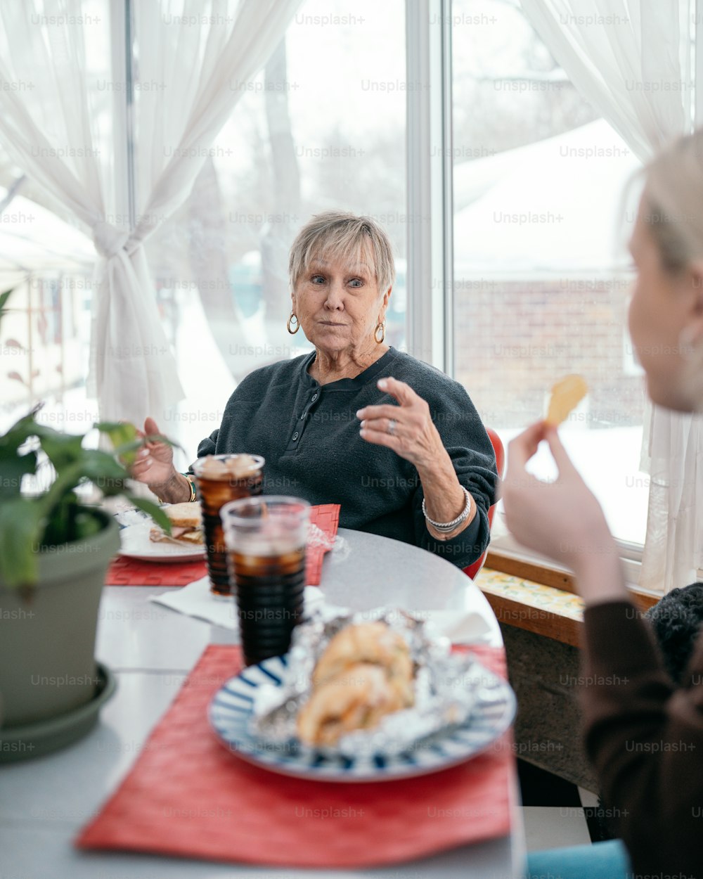 Eine Frau sitzt an einem Tisch mit einem Teller Essen
