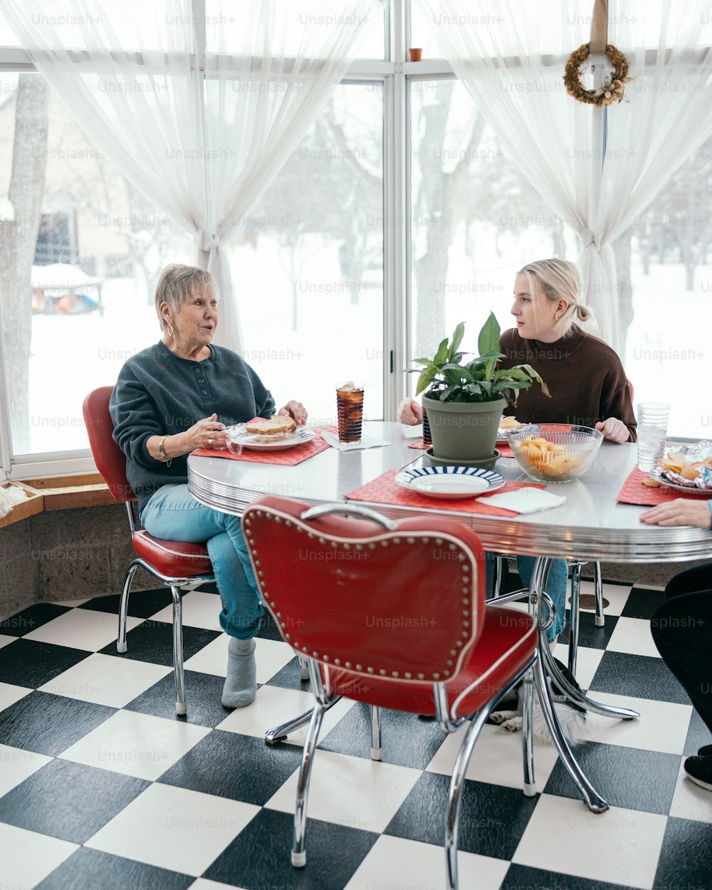 a couple of women sitting at a table with plates of food