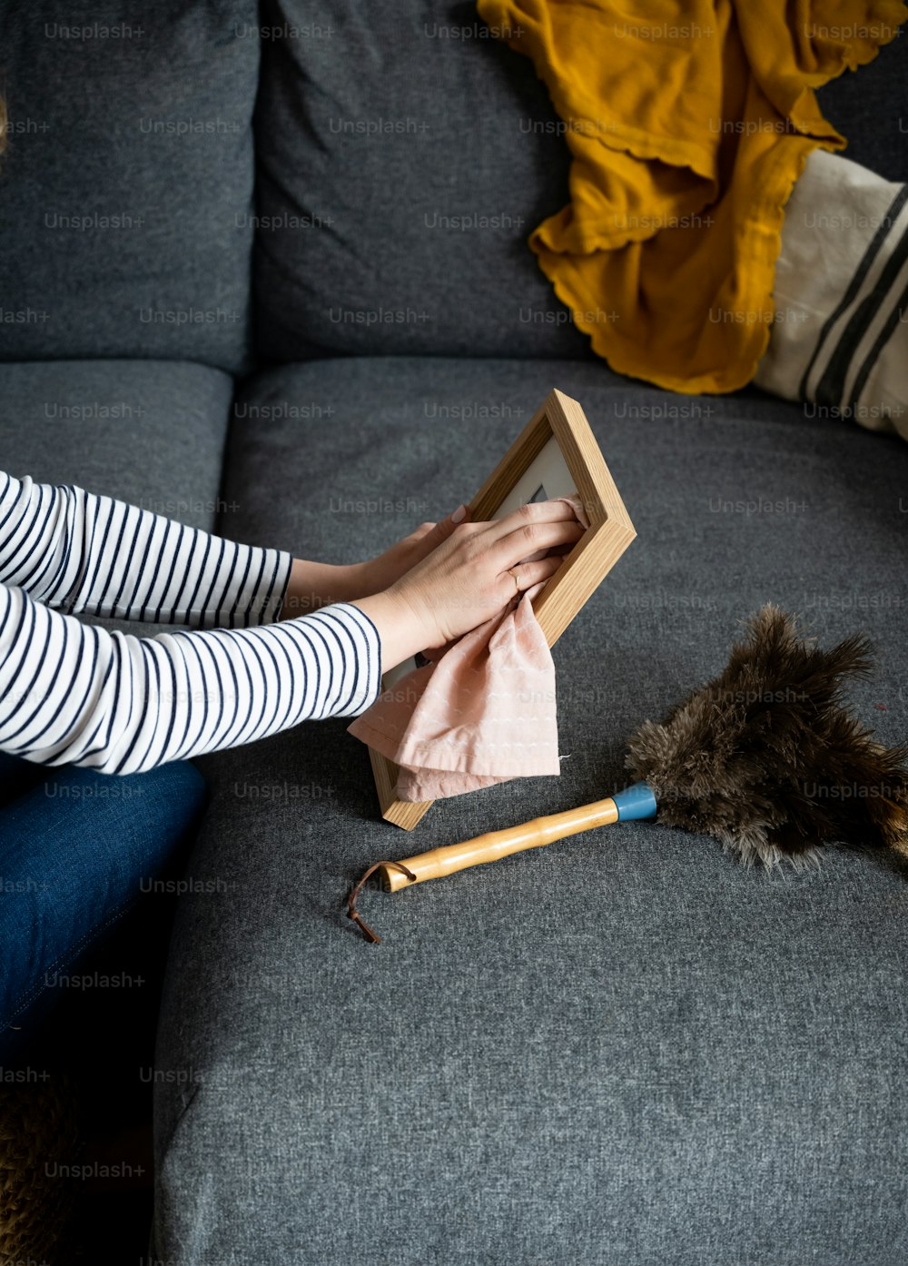 Una mujer sentada encima de un sofá sosteniendo un marco de madera