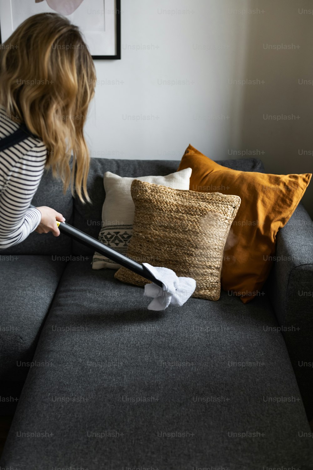 Una mujer limpiando un sofá con un trapeador
