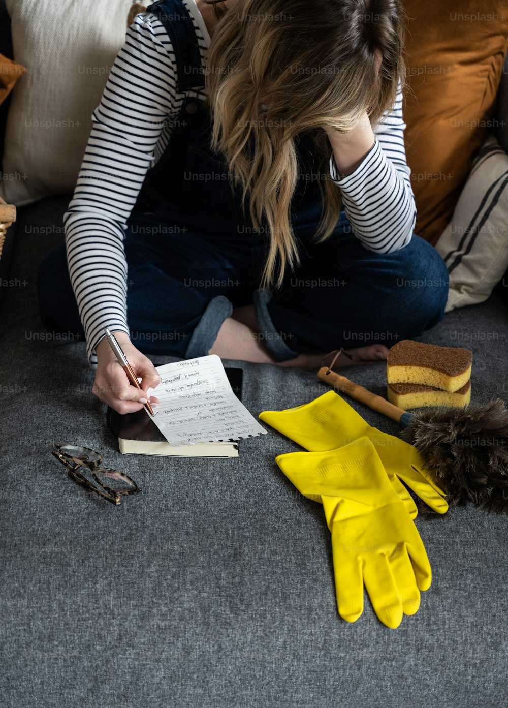 a woman sitting on a couch writing on a piece of paper