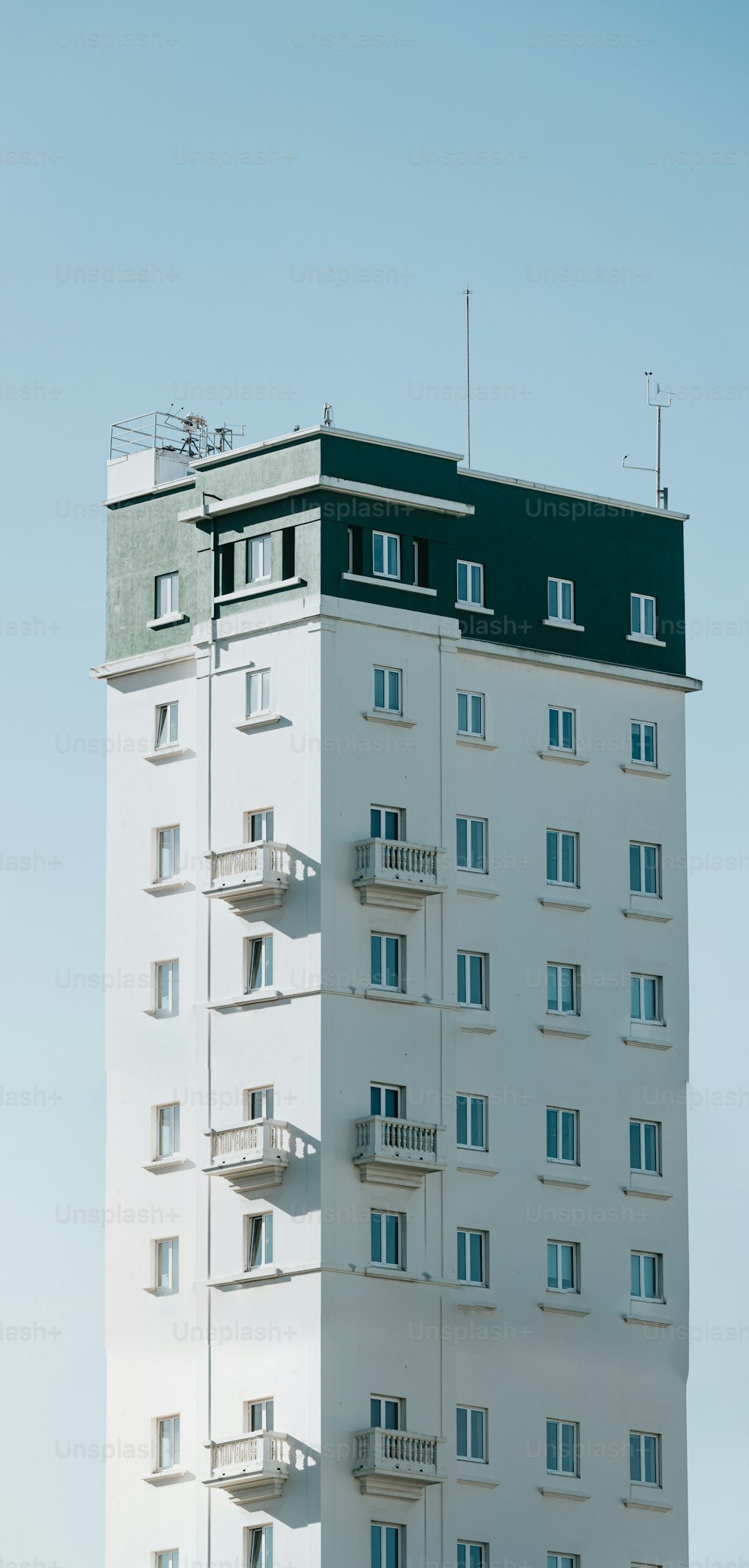 a tall white building with balconies on top of it