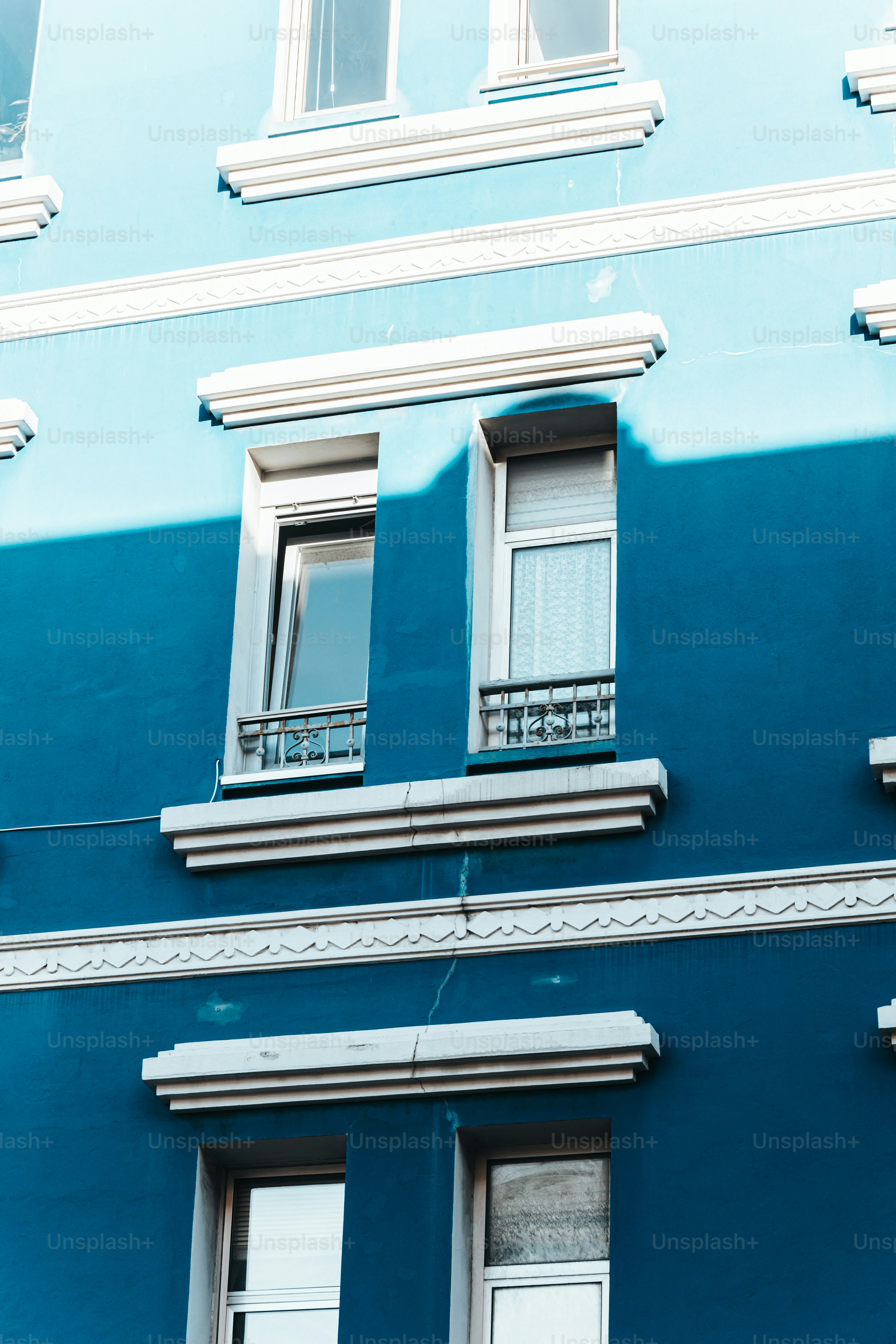 um edifício azul com duas janelas e uma varanda