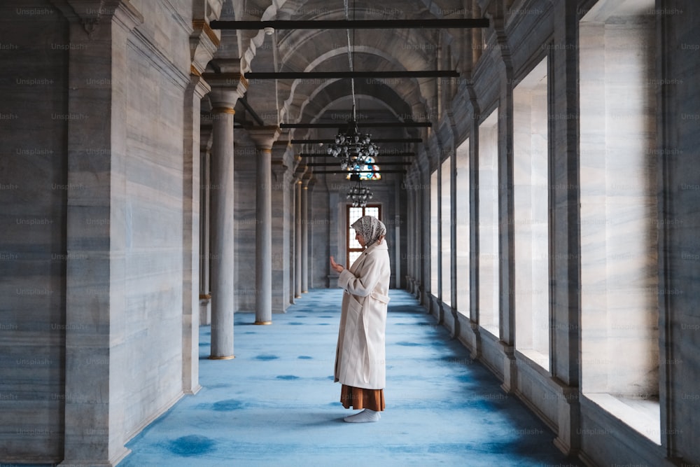 a woman in a white robe standing in a hallway