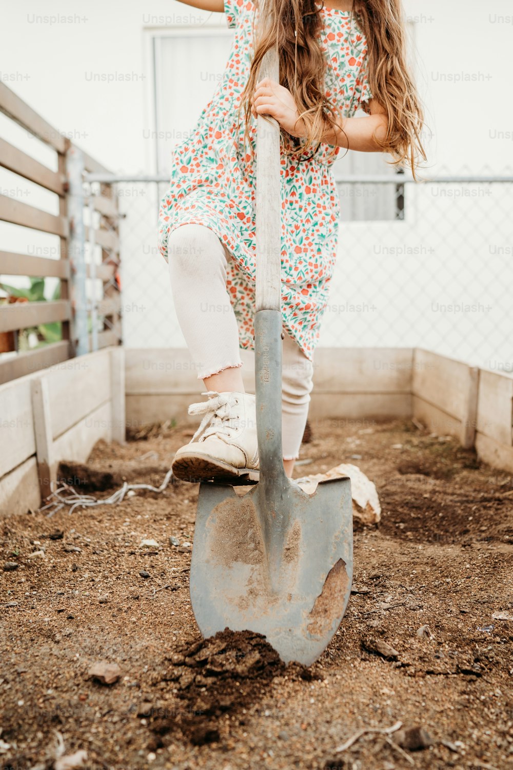 a little girl standing on top of a shovel