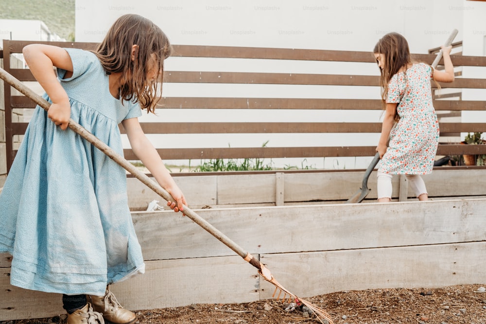 two little girls are playing with a shovel