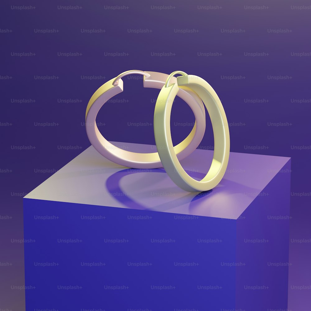 a couple of rings sitting on top of a purple block