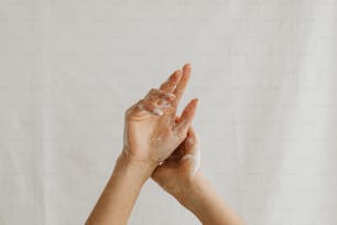 due mani con sapone sui palmi delle mani su uno sfondo bianco