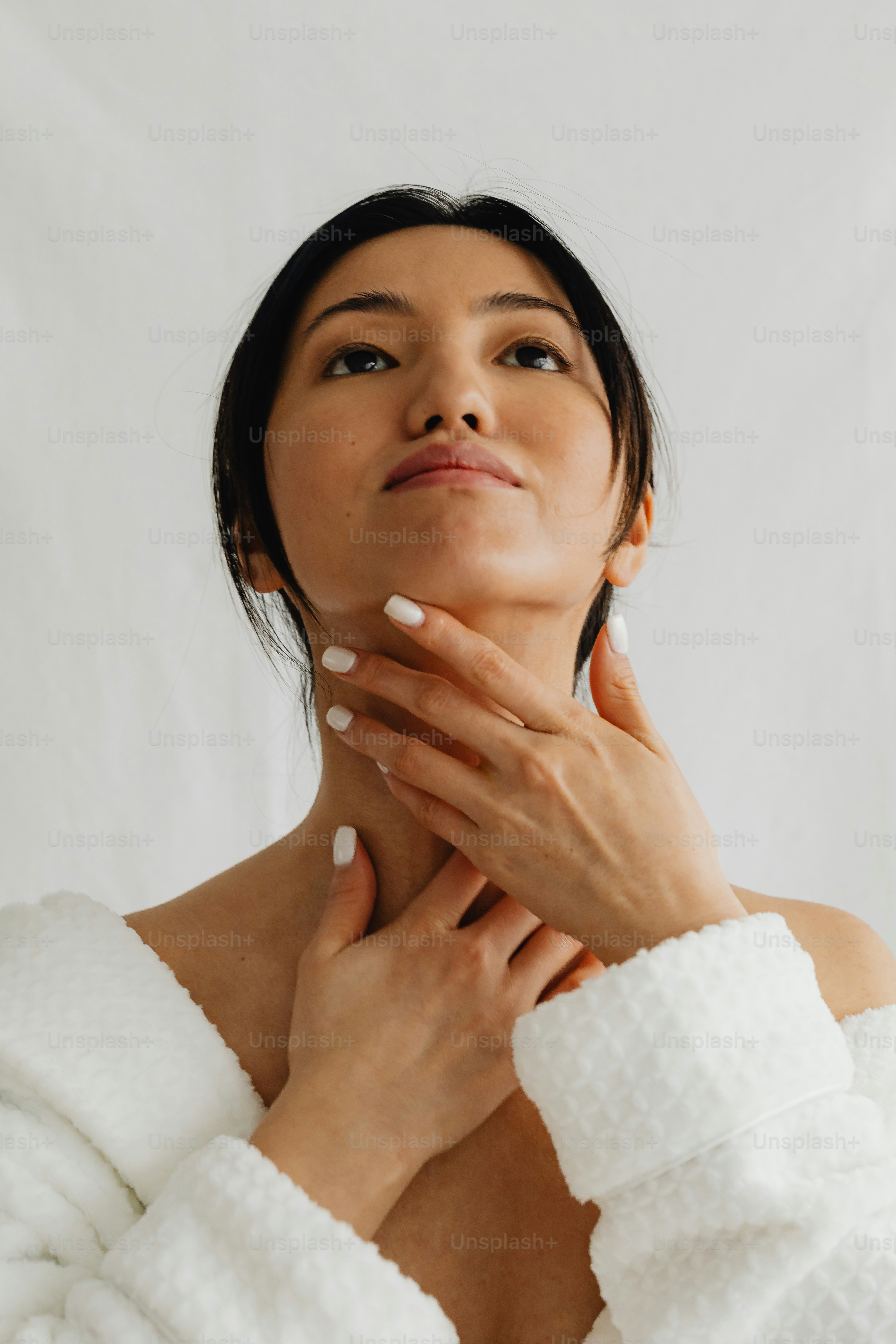 Eine Frau im Bademantel, die sich die Hände vor die Brust hält