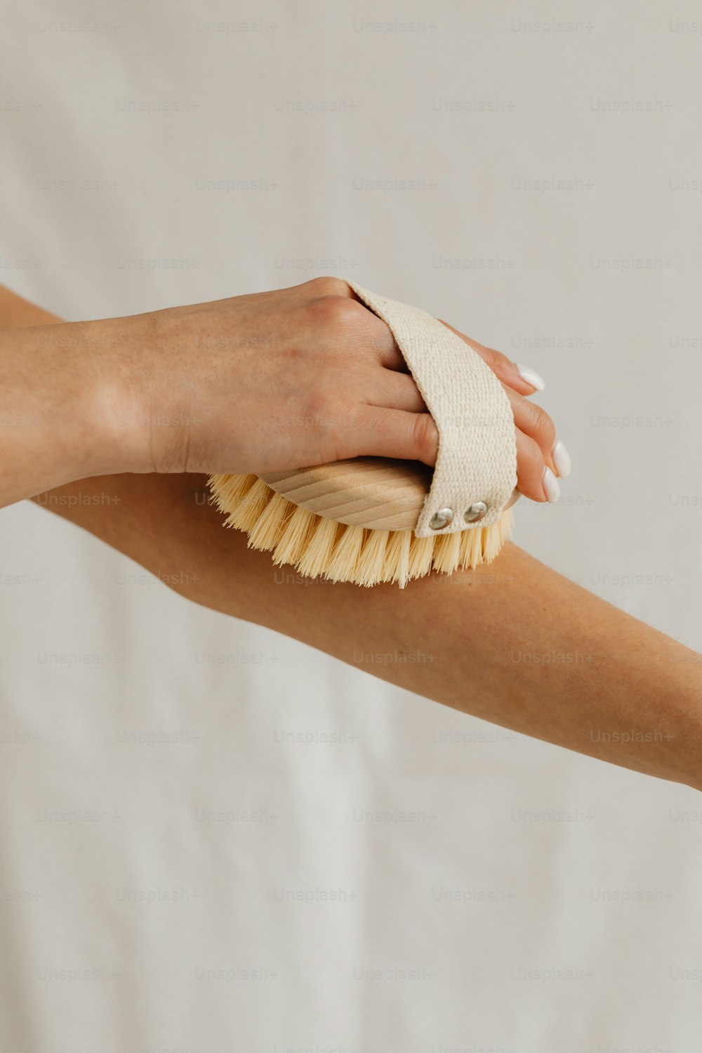 a woman's hand holding a brush on a white background