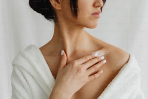 a woman wearing a white towel and holding her hand on her shoulder