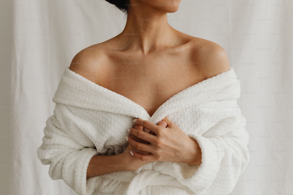 Una mujer envuelta en una toalla blanca posando para una foto