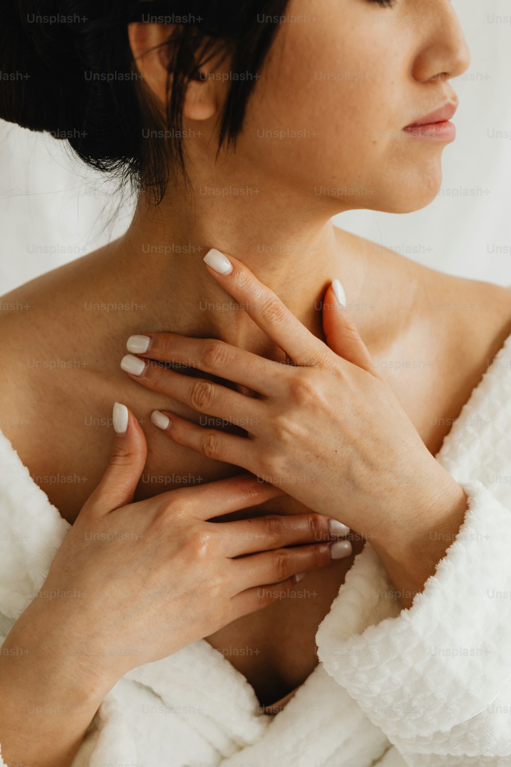 Eine Frau im Bademantel mit den Händen auf der Brust