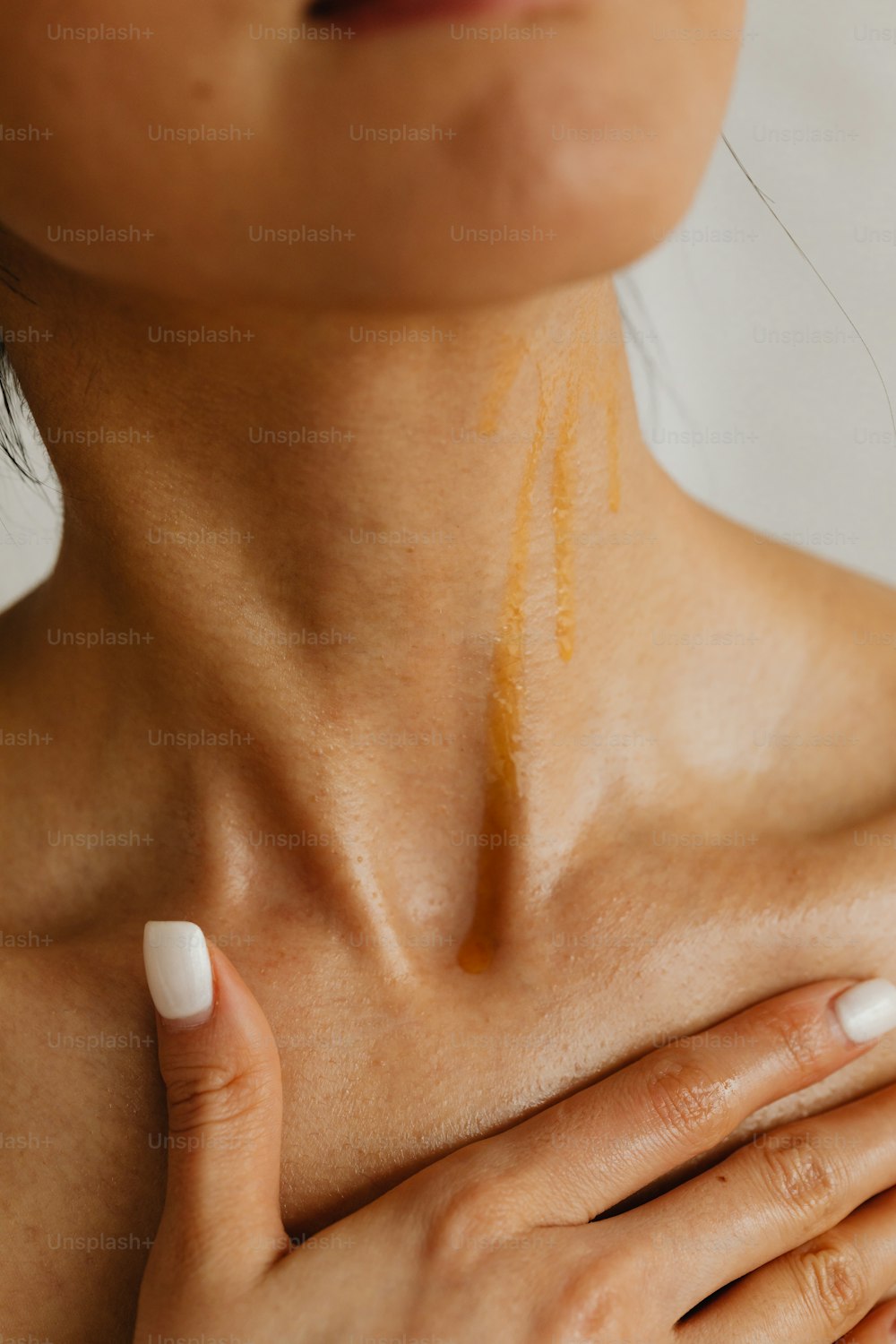 a woman holding her chest with a yellow substance on her chest