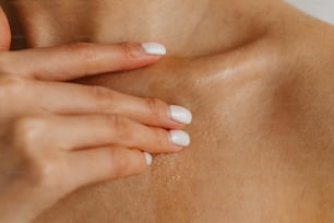 a close up of a woman's breast with white nails