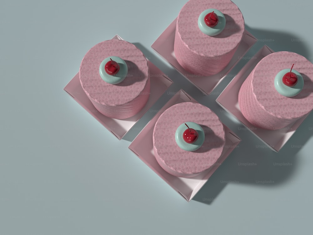 three pink cakes with a cherry on top of them