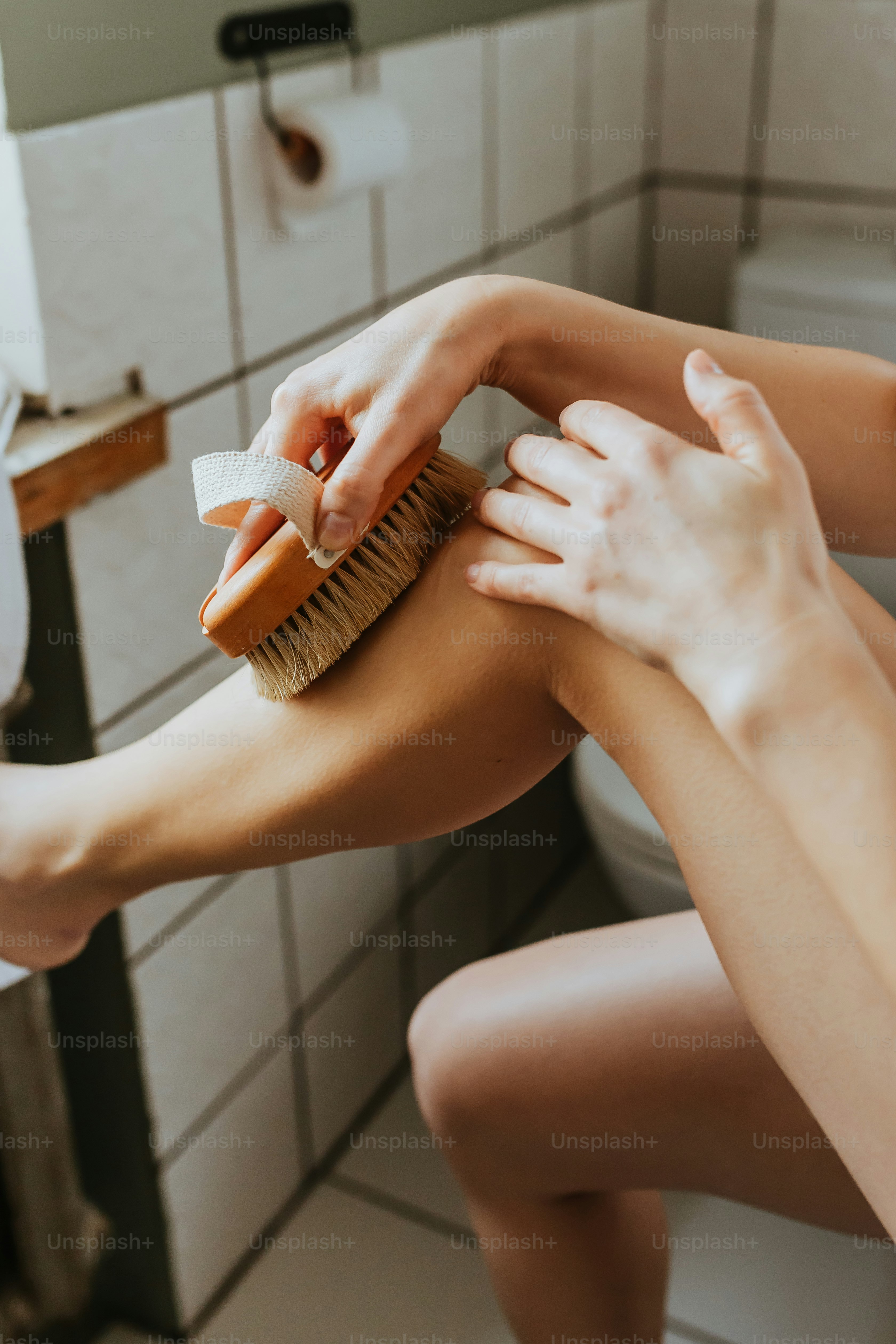 a woman is cleaning her legs with a brush