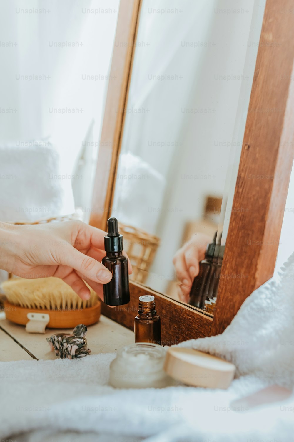 a person holding a bottle of essential oils in front of a mirror