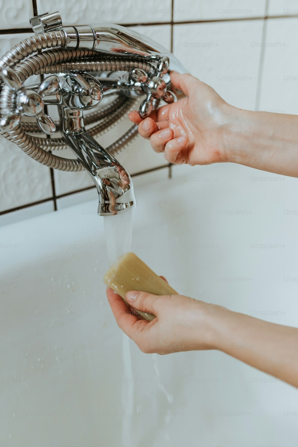 a person is washing their hands under a faucet