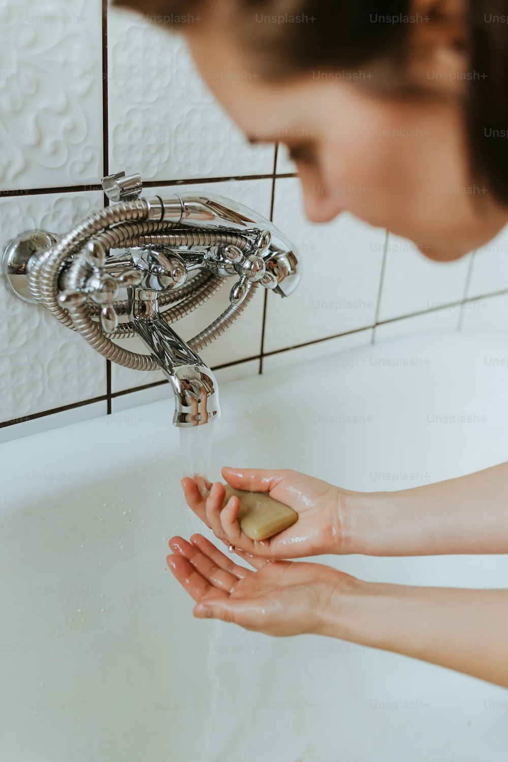 uma mulher lavando as mãos sob uma torneira